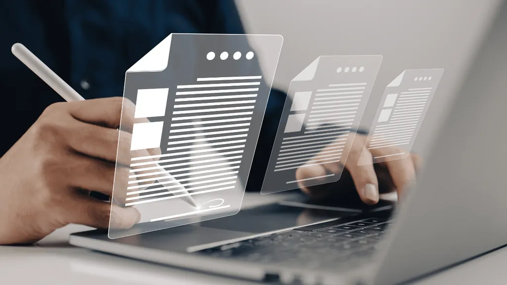 Hand with a stylus beside floating digital documents over a laptop