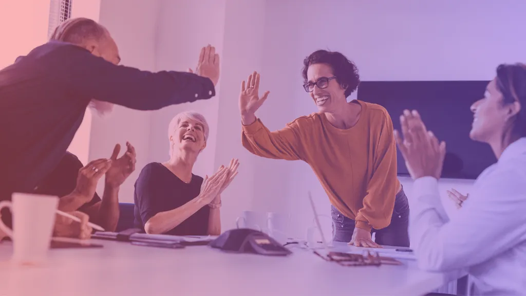 Colleagues giving high fives around a meeting table
